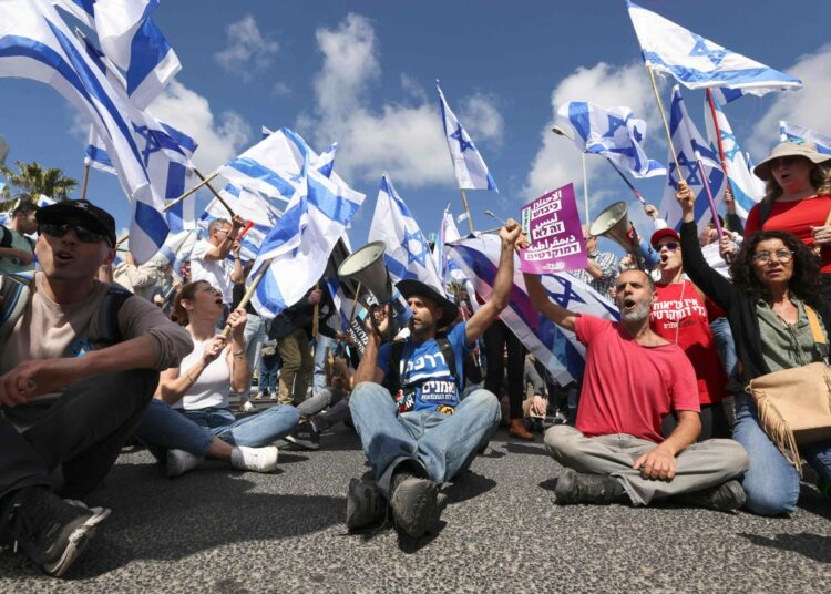 Israelilaisia istumassa kadulla ja osoittamassa mieltään hallituksen oikeuslaitosuudistusta vastaan Haifassa torstaina 9. maaliskuuta.