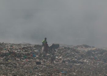 Äiti ja lapsi vaeltavat savupilven läpi Dandoran kaatopaikalla. Se on Kenian suurin avokaatopaikka. Sieltä leviävä savu saastuttaa Nairobin ilmaa.