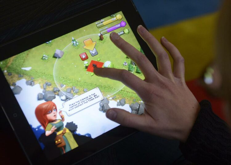 Pelaaja pelaamassa suomalaista, Supercellin suunnittelemaa Clash of Clans -peliä iPadillä.