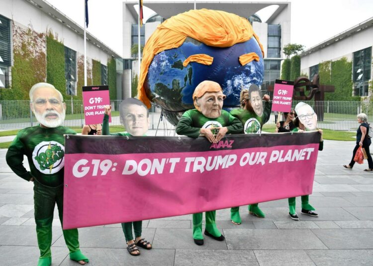 Mielenosoittajat vaativat viime viikolla Berliinissä Saksan liittokanslerin viraston edessä Angela Merkeliä johtamaan G20-maita Donald Trumpin ilmastopolitiikkaa vastaan.