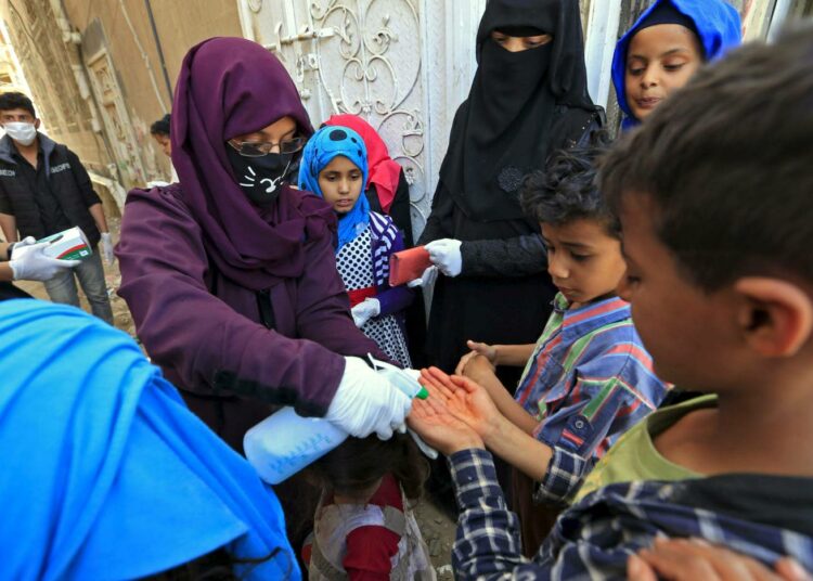 Lasten käsiä desinfioidaan Sanaan esikaupungissa.