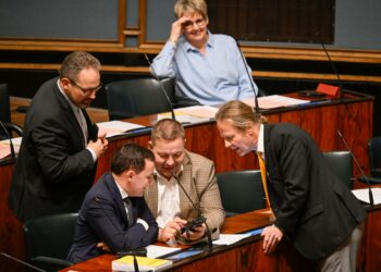 Perussuomalaisten Jani Mäkelä, Wille Rydman, Juha Mäenpää sekä Juho Eerola tutkivat matkapuhelinta eduskunnan täysistunnossa tänään keskiviikkona.