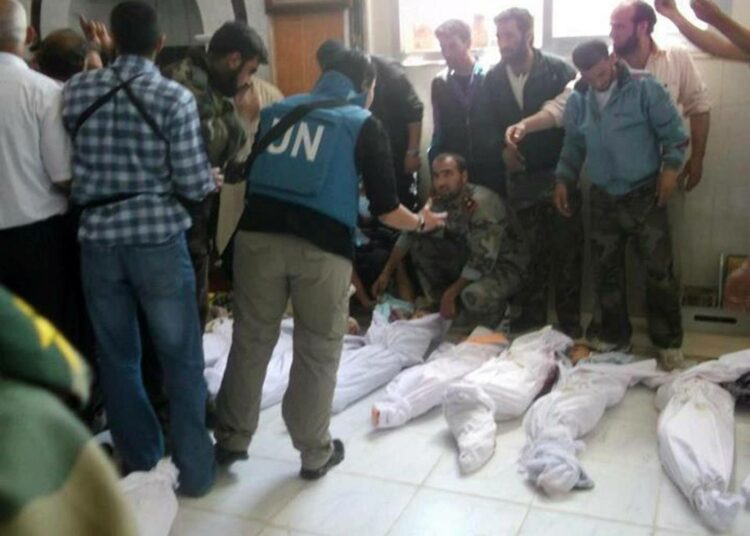 YK:n tarkkailijoita katsomassa ruumishuoneella Houlan joukkomurhassa surmattujen lasten ruumiita ennen hautaamista viime lauantaina.