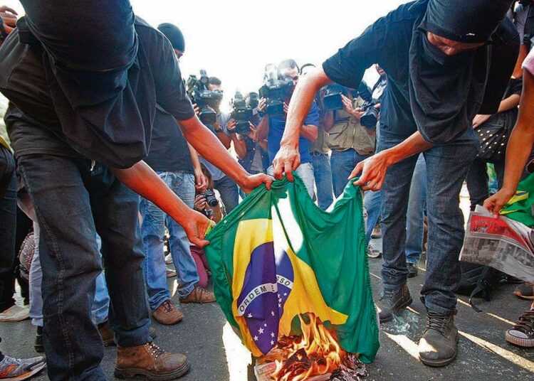 Jalkapallon MM-kisoja vastustavat mielenosoittajat polttivat Brasilian lipun keskiviikkona Goianian kaupungissa Keski-Brasiliassa.