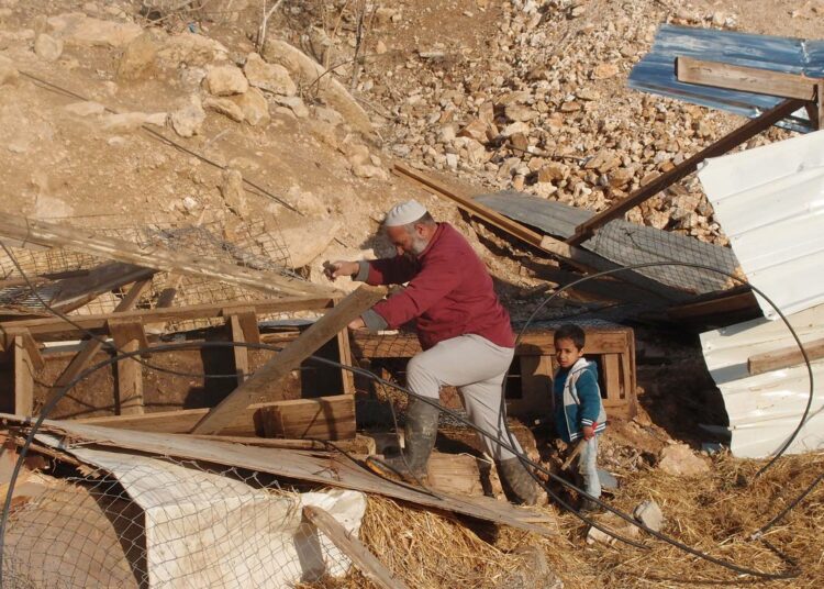Palestiinalainen isä ja poika tuhotun talonsa raunioilla.