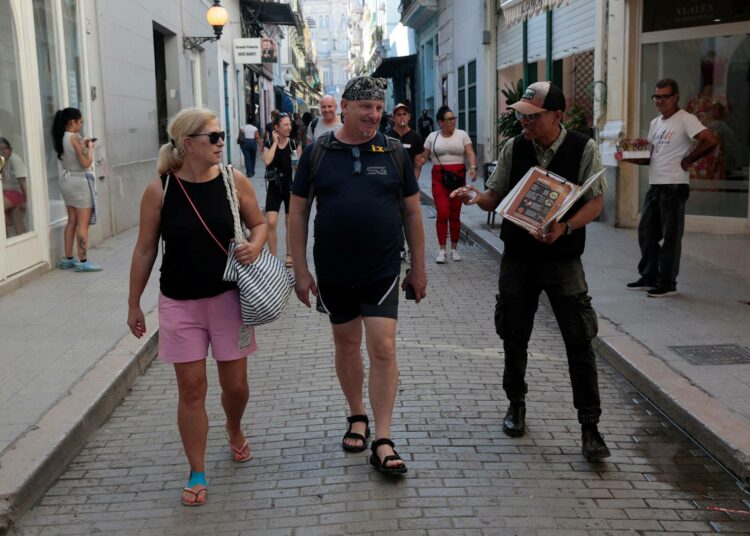 Työntekijä houkuttelee turisteja ravintolaan Havannan kaduilla.