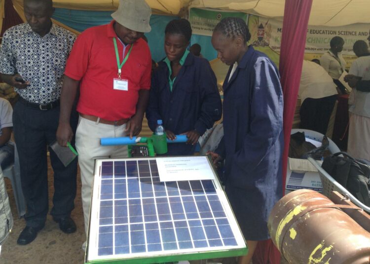 Insinööriksi opiskelevat Emma Masibo (kesk.) ja Lucy Bwire esittelivät opettajansa Peter Wamalwan kanssa aurinkokäyttöistä ruohonleikkuria Kenian tiedeviikolla toukokuussa.