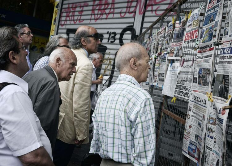 Ihmiset tutkivat lehtien otsikoita maanantaina Ateenassa.