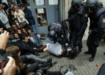 Espanjan poliiseja poistamassa ihmisiä äänestyspaikalta sunnuntaina.