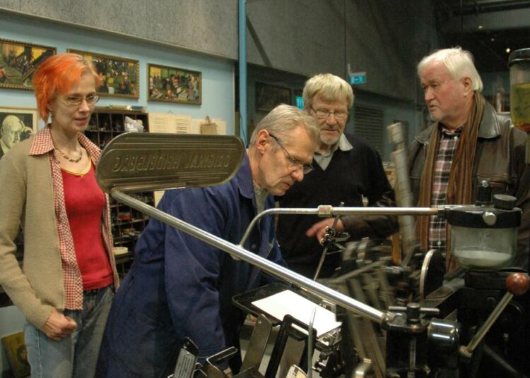 Jussi Kestilä (oik.), Pekka Kuivalahti ja Jaana Kivimäki seuraavat Työväenmuseo Werstaan Museokirjapainossa Raimo Rajalan työskentelyä. Museokirjapaino on toimiva kirjapaino, jonka syntyä kirjallisuuskerhokin on ollut edistämässä.