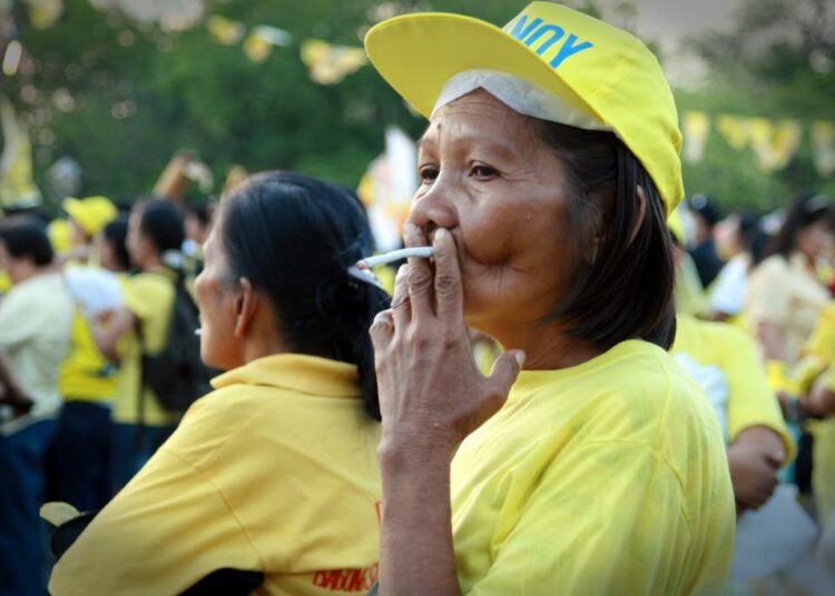 Filippiiniläisnainen polttaa Fortune-merkkistä savuketta vaalitilaisuudessa vuonna 2010.
