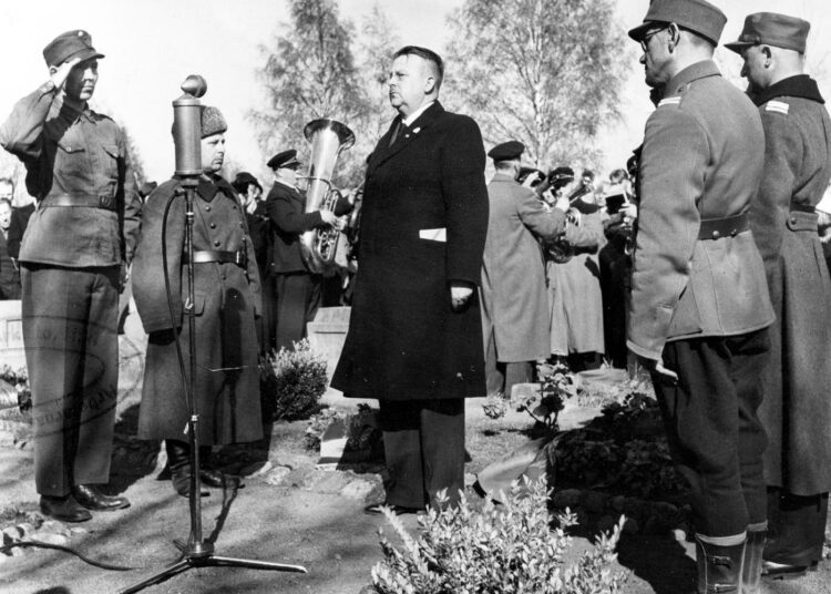 Kunniavartio ja seppeleenlasku Helsingin Malmin hautausmaalla 19. 5. 1940 vuonna 1918 vakaumuksensa puolesta kaatuneiden punakaartilaisten muistoksi. Kuvassa vasemmalla sotamies Edvin Karlsson, sotamies Hugo Westerlund, oikealla edessä alikersantti Eero Meriluoto ja hänen takanaan Väinö Ahde. Muisto-puheen piti toimittaja Yrjö Räisänen (Sasu Punanen).