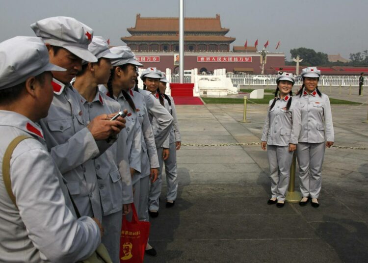 Mao-tyyppisiin asuihin pukeutuneet nuoret kuvaavat toisiaan Tiananmenin aukiolla Pekingissä.