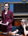 Minja Koskela (vas.) eduskunnan istuntosalissa. Istumassa Aino-Kaisa Pekonen.