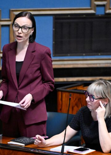 Minja Koskela (vas.) eduskunnan istuntosalissa. Istumassa Aino-Kaisa Pekonen.