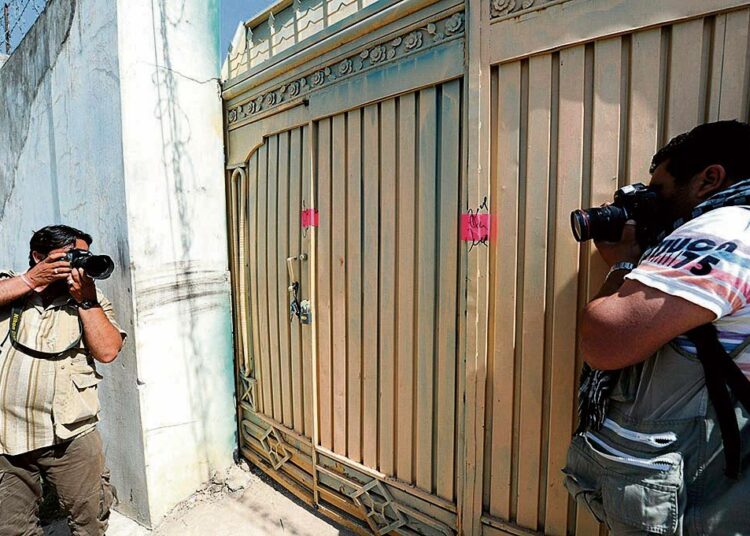 Pakistanilaiset lehtikuvaajat valokuvasivat toisiaan Osama bin Ladenin piilopaikaksi väitetyn talon portin edustalla Abbottabadissa toukokuun alussa. Paikalliset asukkaat eivät usko, että Osama bin Laden olisi asunut kaupungissa.