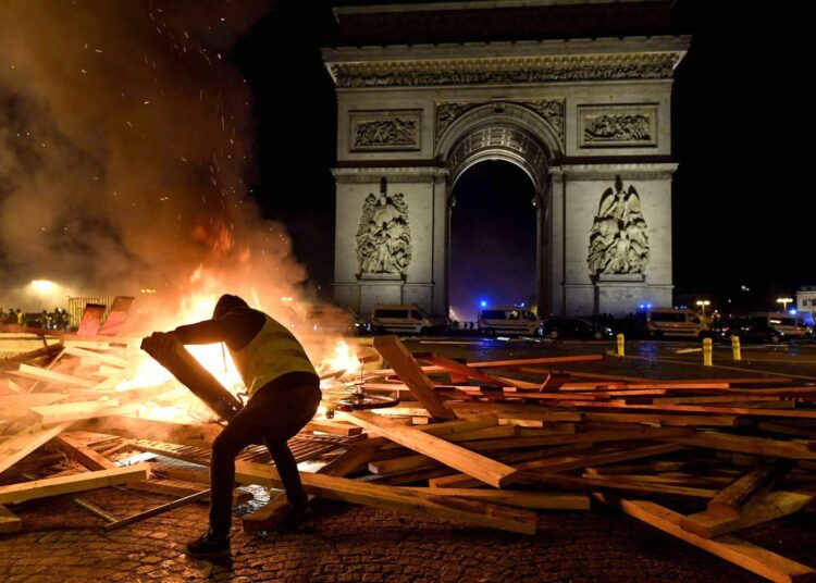 Keltaliivinen mielenosoittaja lisäsi puuta rovioon Pariisin Riemukaaren lähellä toissa viikonloppuna.