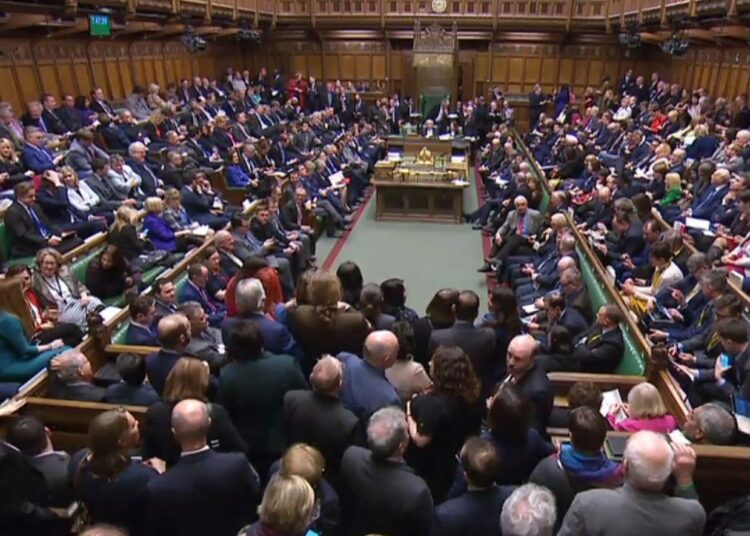 Britannian parlamentissa on tiivis tunnelma, kun kansanedustajat istuvat vieri vieressä.