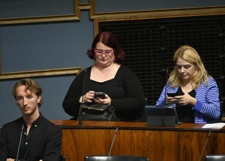 Pia Lohikoski (keskellä) eduskunnan istunnosssa.
