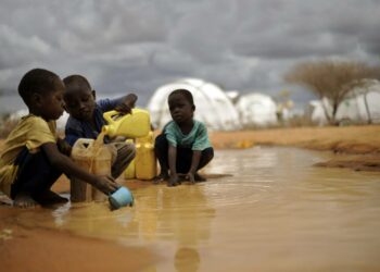 Somalipojat täyttävät juoma-astiaa sateen jälkeen Kenian Dadaabin pakolaisleirissä.