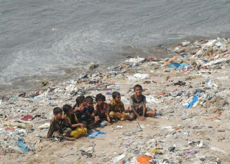 Mumbailaiset lapset leikkimässä muovin peittämällä rannalla.