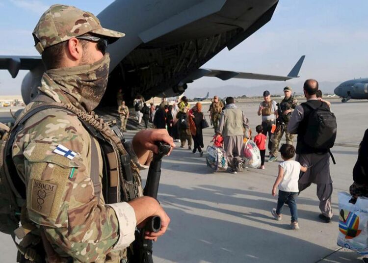 Lopulta Suomi evakuoi myös suurlähetystössä alihankitayrityksen palveluksessa olleita afgaaniturvamiehiä perheineen. Kuvassa Puolustusvoimien suojausjoukon sotilaita ja evakuoitavia ihmisiä Kabulin lentokentän alueella
