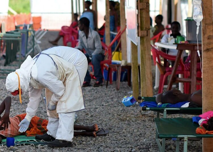 Hoitaja tutkii ebolapotilasta Kenamassa Sierra Leonessa.