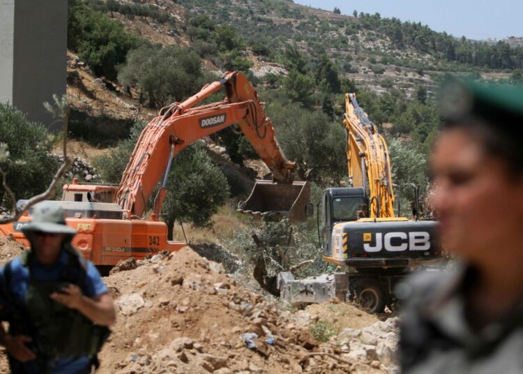 Israelin sotilaat pitivät vahtia, kun kaivinkone raivasi oliivipuita rakennettavan suojamuurin tieltä Beit Jalassa Länsirannalla.