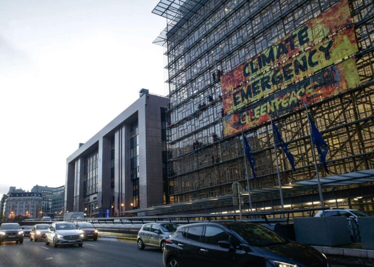Greenpeacen aktivistit levittivät keskiviikkona ilmastohätätilasta muistuttavan banderollin EU:n virastorakennuksen seinään Brysselissä.