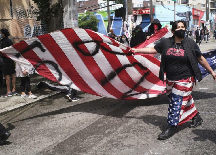 Seattlelainen mielenosoittaja kantoi Yhdysvaltojen tähtilippua, johon oli spraymaalattu sanat rakkaus ja raivo.