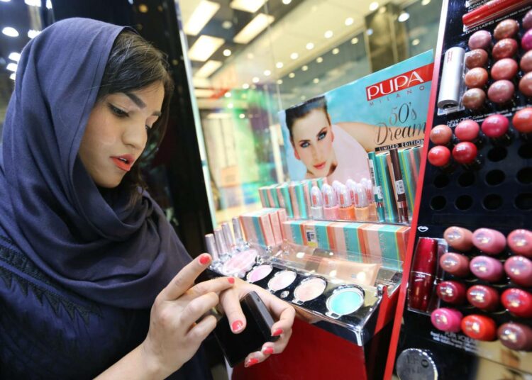 Iranilaisnainen tutkimassa kosmetiikkavalikoimaa teheranilaisessa myymälässä.