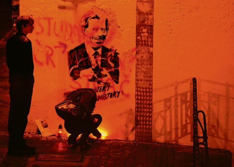 Ihmiset sytyttivät maanantaina kynttilöitä Vaclav Havelia esittävän graffitin edessä Prahassa.