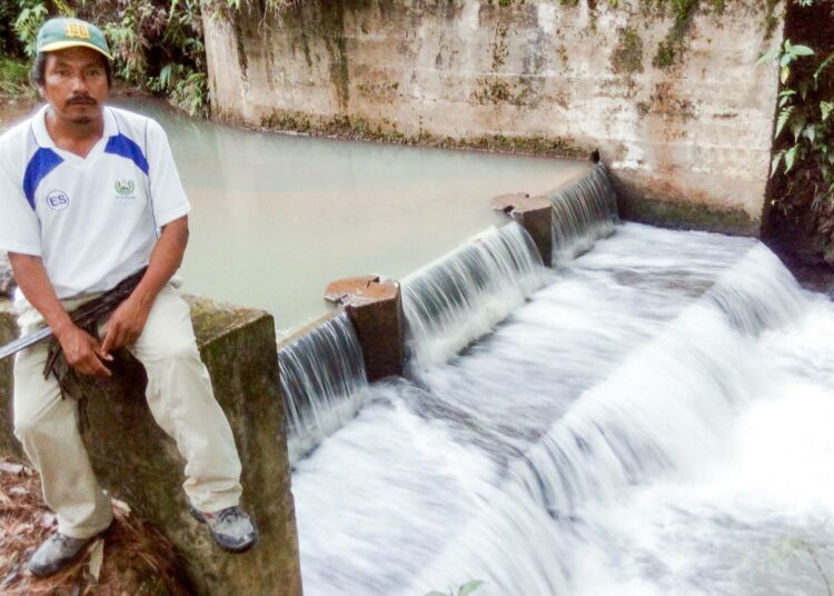 Juan Benitez istuu El Calambren pienvesivoimalan padon reunalla. Runsaan 40 perheen kylä on itse rakentamansa voimalan ansiosta nauttinut sähköstä vuodesta 2012.