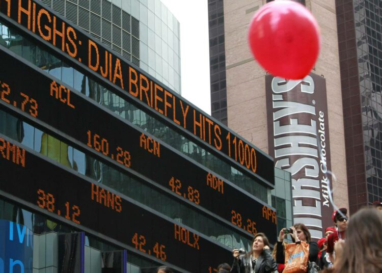Turisteja ottamassa kuvia Dow Jones -indeksin tilanteesta Morgan Stanleyn digitaululta New Yorkissa.