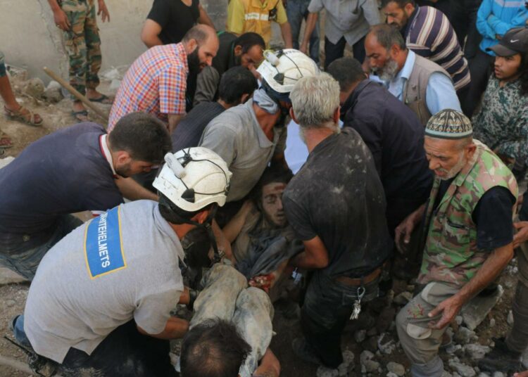 Valkokypäriksi kutsutut vapaaehtoiset nostamassa miehen ruumista raunioista Aleppossa.