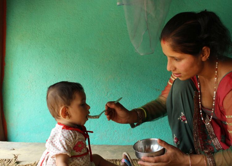 Naisten tarvitsemat lääkkeet eivät ole olleet Nepalin terveysviranomaisten hankintalistojen kärkipäässä. Siksi esimerkiksi YK:n väestörahaston toimittamat ehkäisyvälineet ovat tulleet suureen perhesuunnittelutarpeeseen. Kuvassa Sadhana Ghimire, 23, ruokkii 18 kuukautta vanhaa tytärtään ravitsevalla linssipuurolla.
