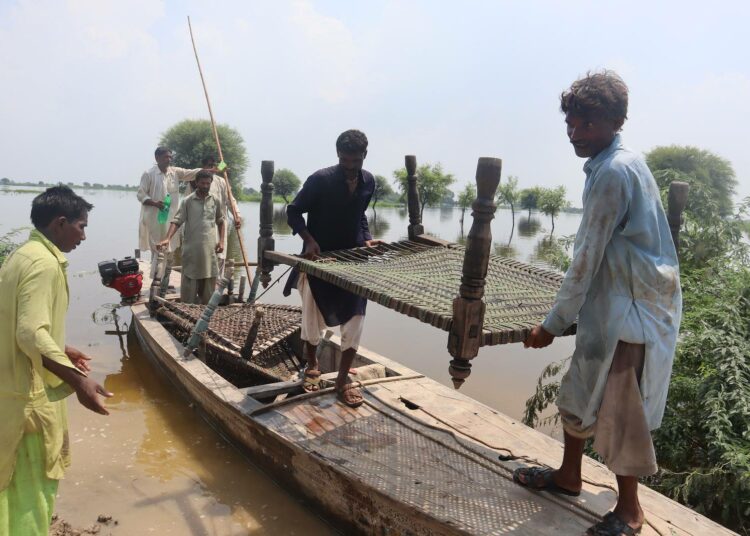 Venemiehet tuovat kuivalle maalle veden alle vaipuneesta kylästä pelastamiaan köysisänkyjä.