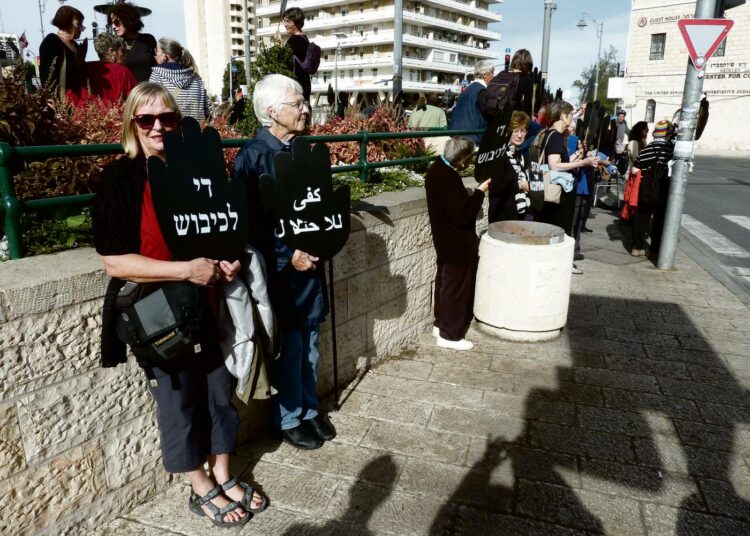Polly Amrein (oikealla) Women in Black -järjestön mielenosoituksessa Länsi-Jerusalemissa. Kylteissä lukee arabiaksi ja hepreaksi ”Lopettakaa miehitys”.