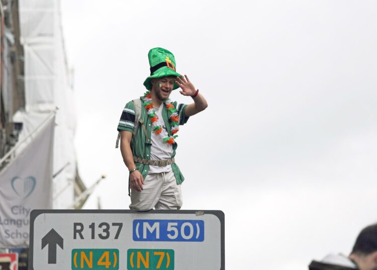 Irlantilaismies kiipesi liikennemerkin nokkaan Pyhän Patrickin päivän juhlassa Dublinissa maaliskuussa.