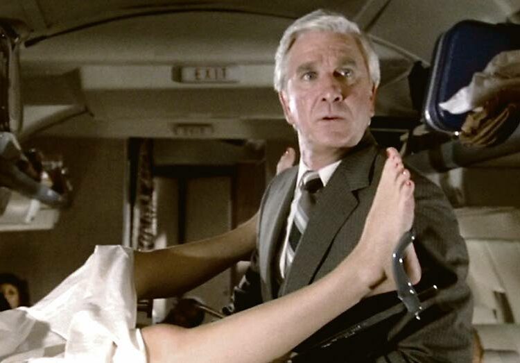 Leslie Nielsen teki läpimurtonsa onnettomana koheltajana Hei me lennetään -elokuvassa. Sama meno jatkui sittemmin Mies ja alaston ase -trilogiassa.