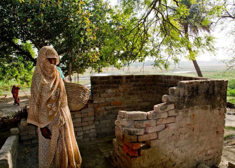 Intian Manipurissa Uttar Pradeshin osavaltiossa kastiton nainen seisoo yläkastisen omistaman kuivakäymälän ulkopuolella. Intiassa käymälöiden puhdistaminen kuuluu alimmille kasteille