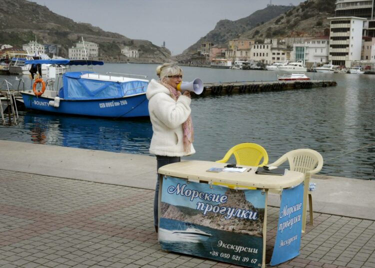 Matkaopas kutsuu asiakkaita Balaklavan satamassa Krimillä. Turismi Krimillä on vähentynyt puoleen ja matkailijoita tulee lähes pelkästään Venäjältä.