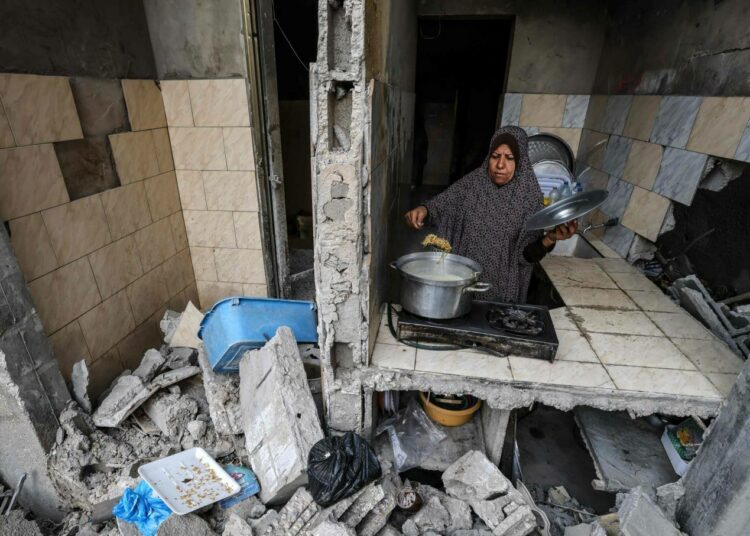 Palestiinalaisnainen valmistaa ruokaa kotinsa jäännöksissä Gazassa.
