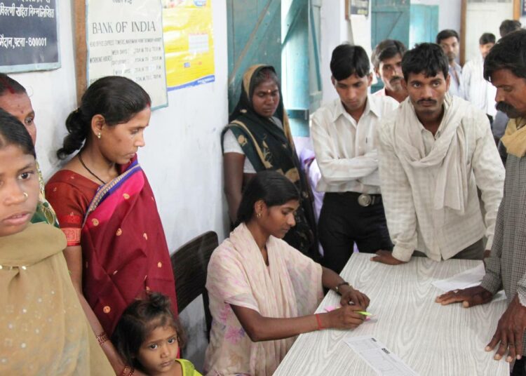 Rinki Kumar auttaa pankin asiakkaita kaavakkeiden täytössä Intian Biharin osavaltiossa sijaitsevassa Sahdeokhapin kylässä.