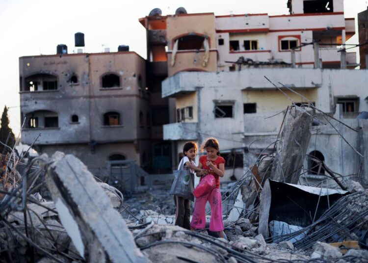 Shahed Abood, 7, (oikealla) ja hänen serkkunsa Ali, 9, etsivät tavaroitaan pommitusten tuhoamasta kodistaan Jabaliyassa maanantaina.