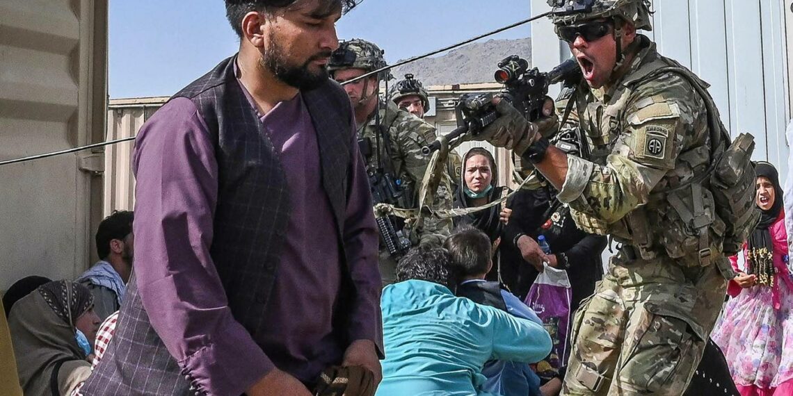 Kabulin lentokentän kaaoksessa yhdysvaltalaissotilas osoittaa aseellaan afganistanilaismatkustajaa.