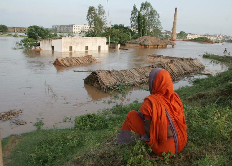 Intian Odishan osavaltiossa asuva nainen katselee tulvaveden armoille jäänyttä kotiaan. Ilmastonmuutos voimistaa äärimmäisiä sääilmiöitä kaikkialla maailmassa.