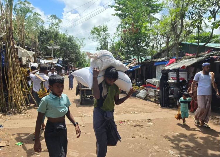 Pakolainen kantaa perheensä ruoka-annosta WFP:n jakelupisteestä suojaansa Balukhalissa Bangladeshissa.