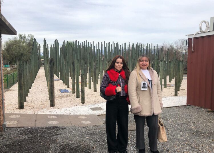 Corporación Memorial Paine -järjestön johtajat Amparo Gaete ja Myriam Sepúlveda seisovat mosaiikkien ja puuveistoksen edessä. Muistomerkki on omistettu 70 maanviljelijälle, jotka pidätettiin ja katosivat Painessa sotilasvallankaappauksen jälkeen.