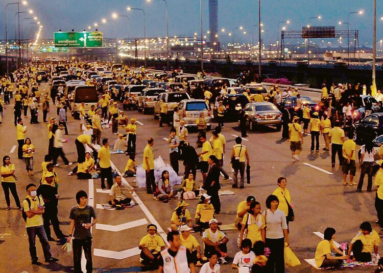 Keltaisiin paitoihin pukeutuneita opposition mielenosoittajia Bangkokin kansainvälisen Suvarnabhumin lentokentän luona tiistaina.
